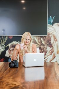 woman working on desk, with computer and drinking coffee